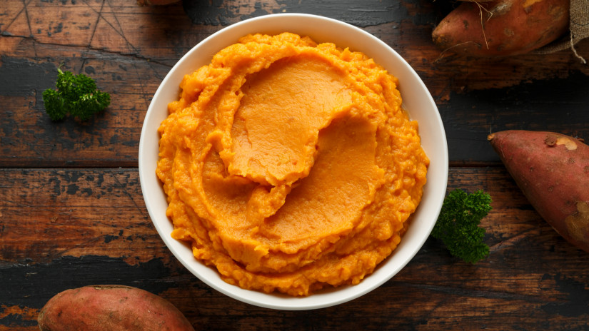 Mashed Sweet Potatoes in white bowl on wooden rustic table. Healthy food.