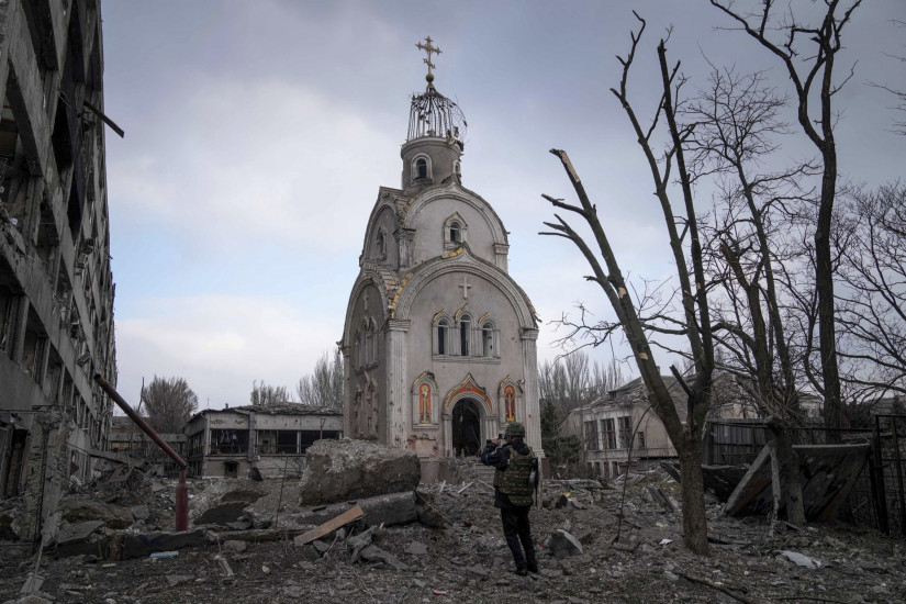 Az egyik templom maradványait fotózza egy ukrán katona megsemmisült épületek romjai között a délkelet-ukrajnai Mariupolban2022. március 10-én. (MTI/AP/Jevhen Maloletka)