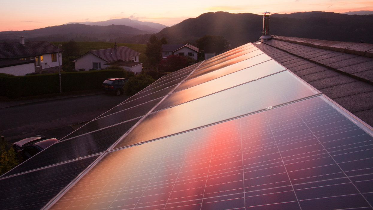 Sunset over a house in Ambleside, Lake District UK, with a 3.8 Kw solar electric panel system on the roof.