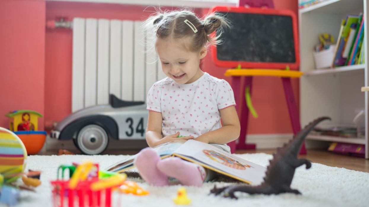 toddler girl playing and reading in the children room
