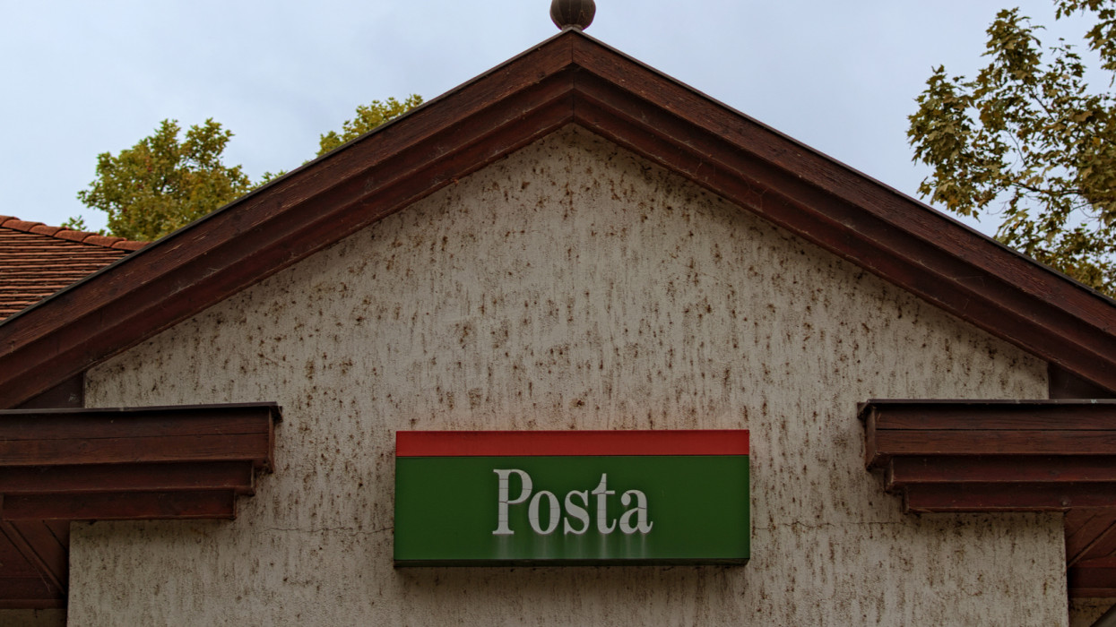 Upper part of the facade of the post office with a sign POSTA (eng. post office) in Balatonfoldvar, Hungary. Cloudy autumn sky at the background. High perspective view.