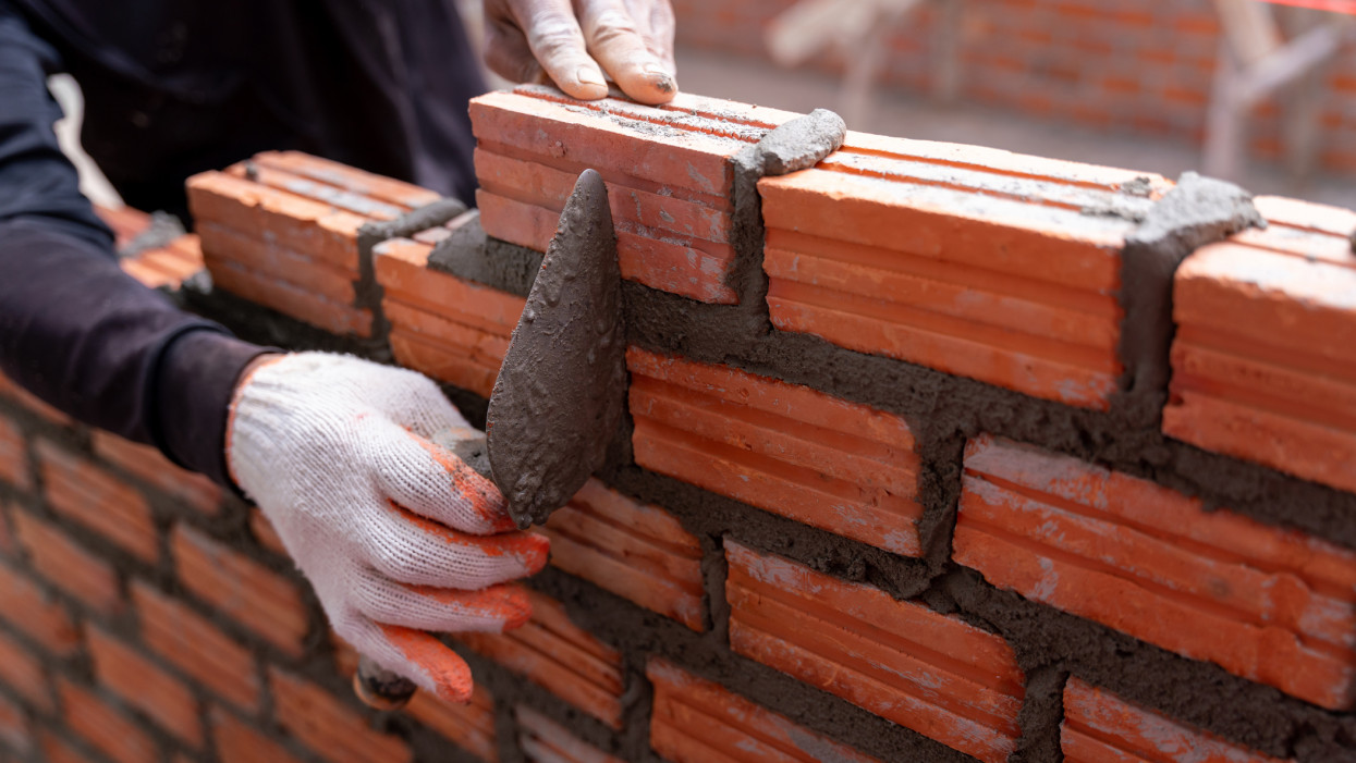 Close up hand of bricklayer worker installing bricks on construction site