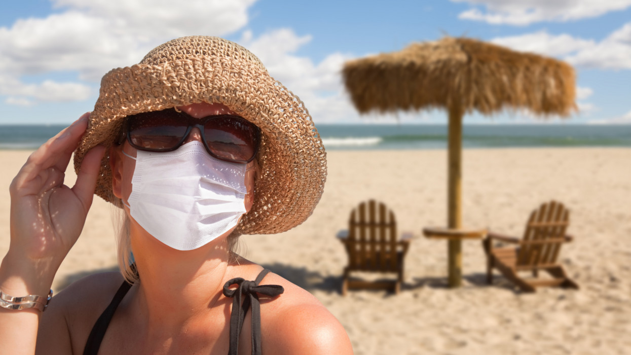 Vacationing Woman Wearing Face Mask on Sandy Beach..