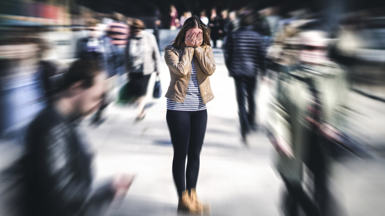 Panic attack in public place. Woman having panic disorder in city. Psychology, solitude, fear or mental health problems concept. Depressed sad person surrounded by people walking in busy street. cimlapi