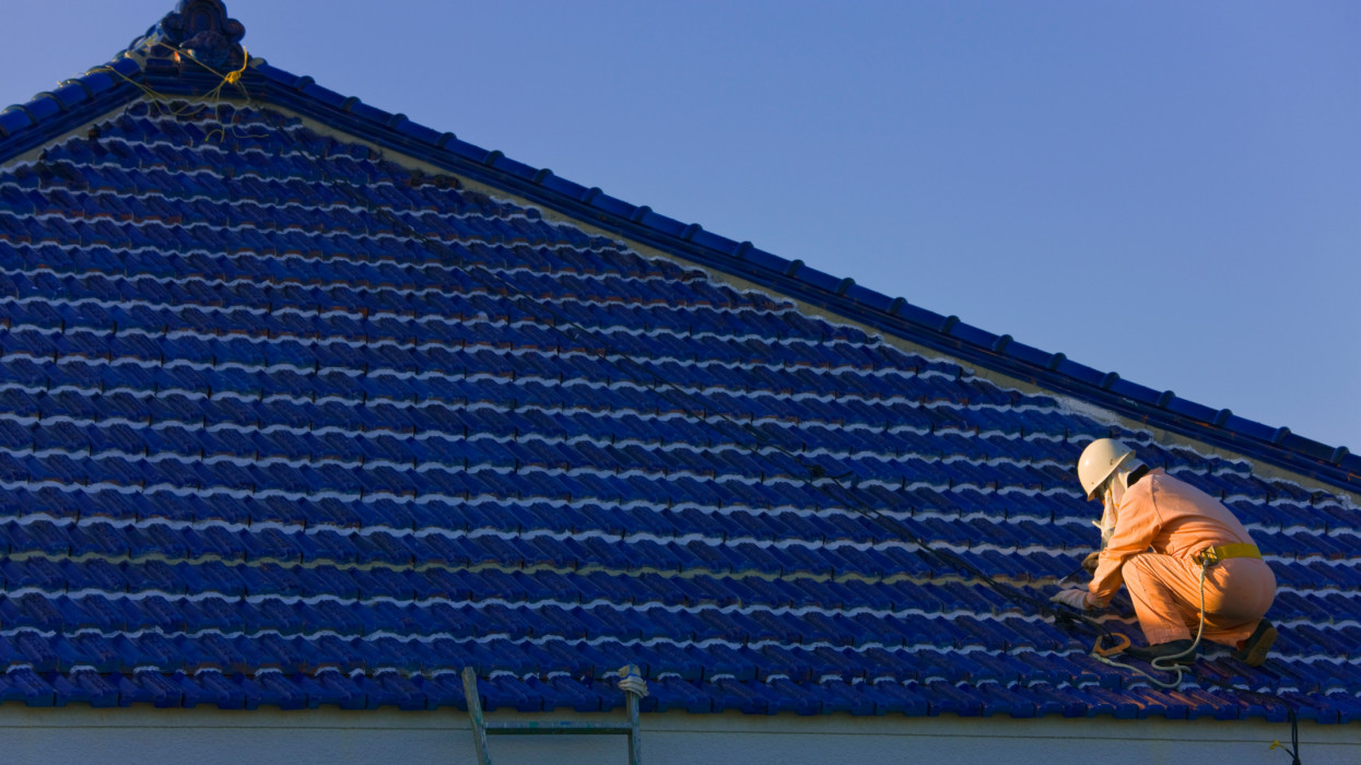 A worker finishes a fresh re-coating of the kawara ceramic tile roof of a traditional residence on tiny Ikeijima Island, located off the central-eastern coast of the main island in Japans Okinawa Prefecture.