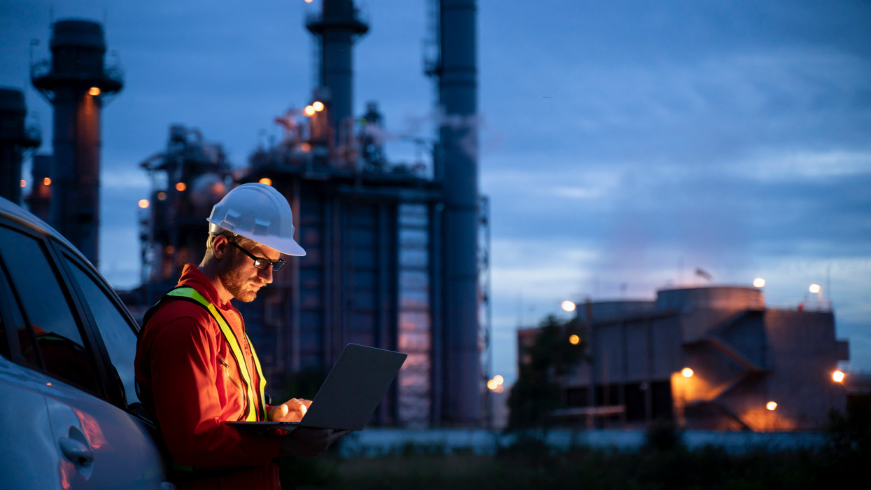 Petrochemical engineers work slowly and heavily with smart tablets in the oil and gas industry at night.