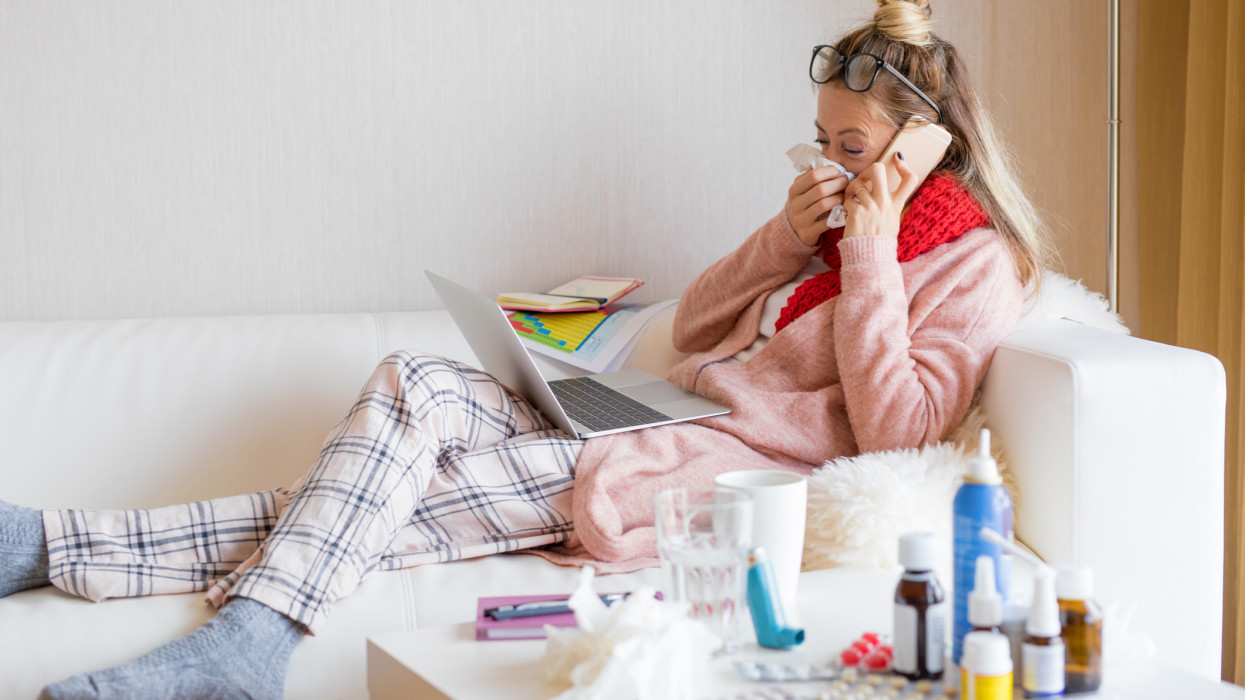 Sick woman working on laptop from home