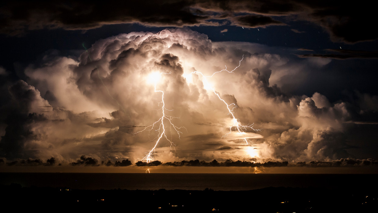 Storm clouds shroud an electrical storm of the coast of  Byron Bay at night. Taken from the hinterland around Mullumbimby, early evening in Autumn as the changing sky dazzles with a natural light show of lightning bolts and billowing clouds dance in the sky for hours.