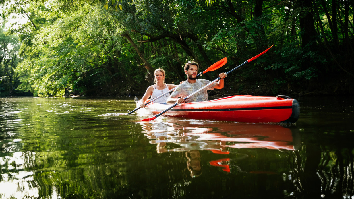 A couple exploring a canal together while paddling in a large kayak.