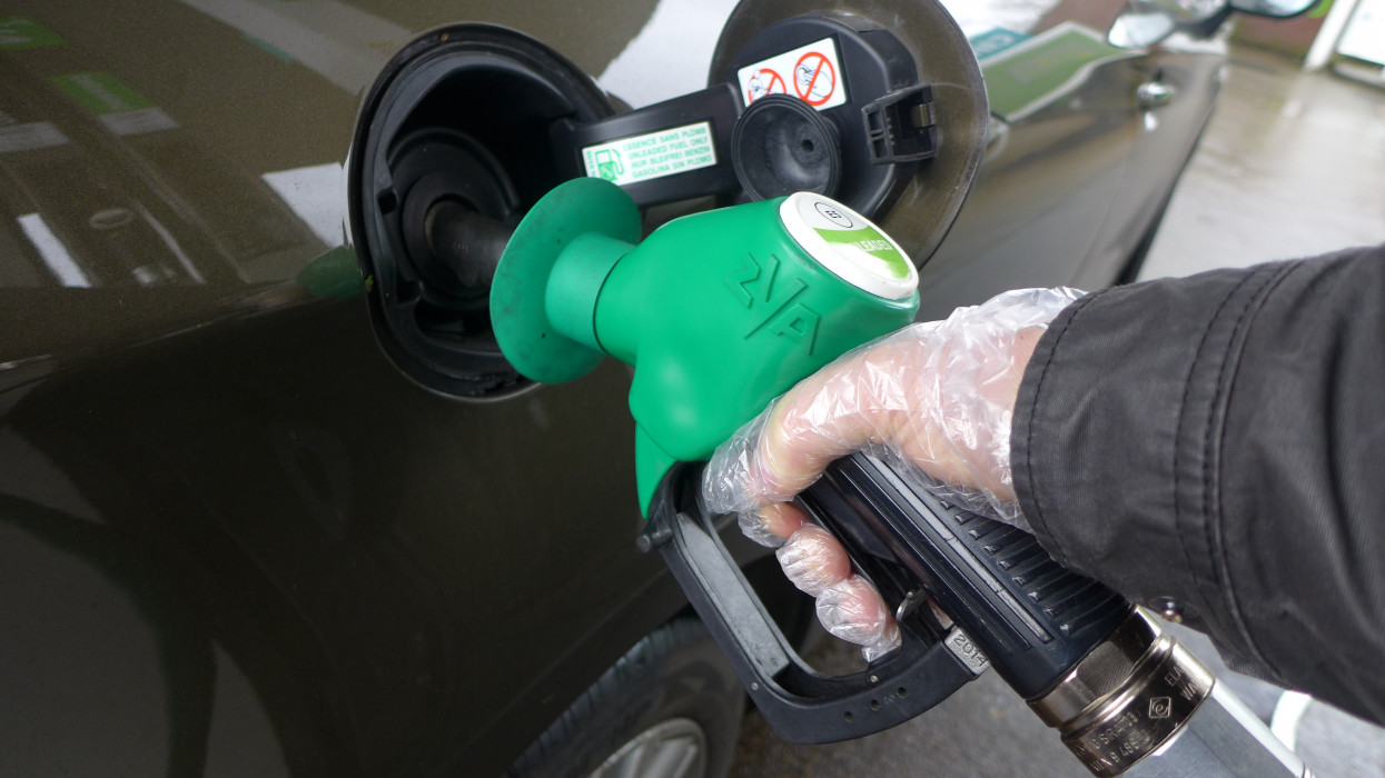 Man hand with glove holding a green no lead gasoline dispenser