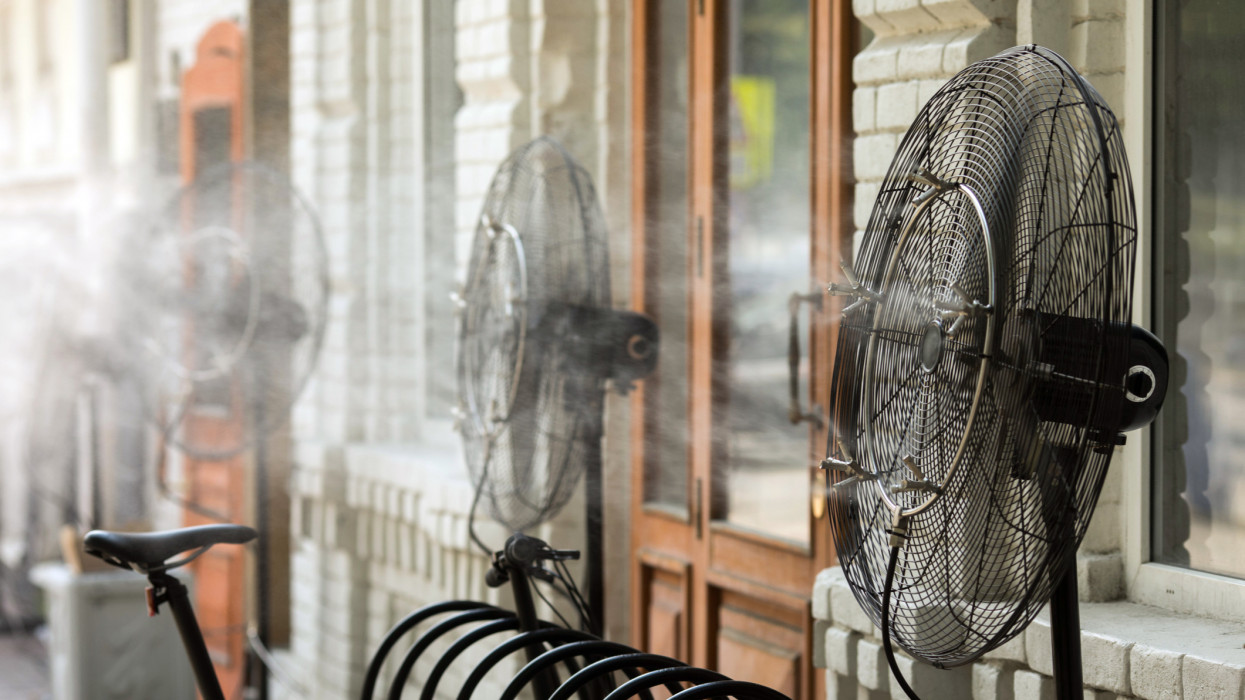 Contemporary system of fans with pulverizes spraying water with air and cooling air outdoors in hot summertime