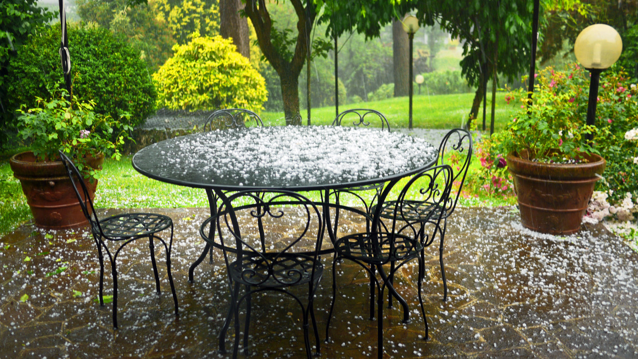 Italian formal garden with wrought iron table and chairs under heavy storm.