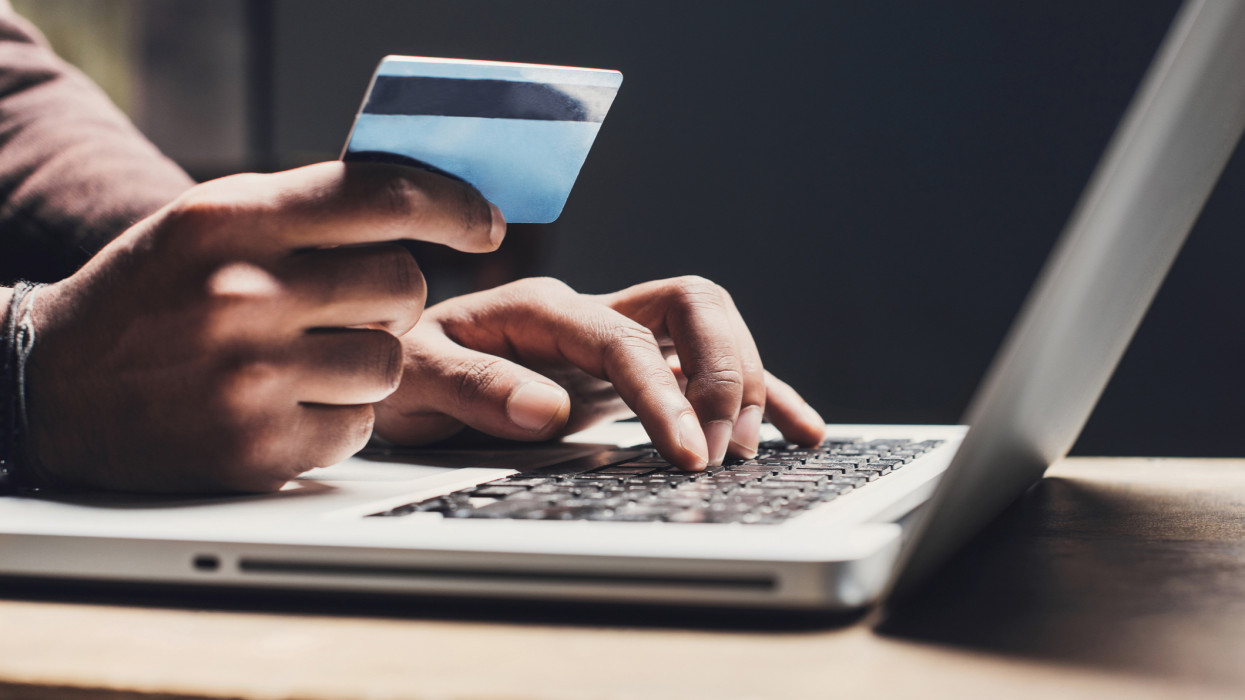 Men entering credit card information using laptop computer keyboard. Online shopping concept