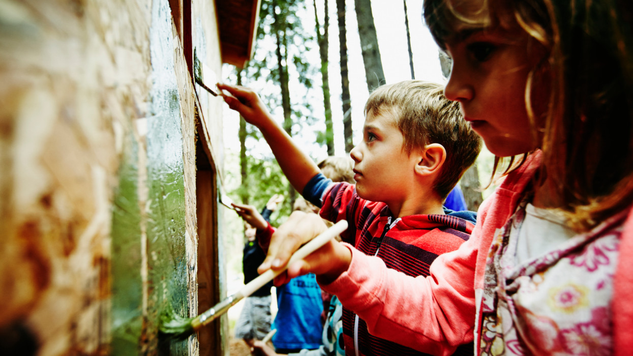 Group of young kids painting outside of fort in woods at summer camp