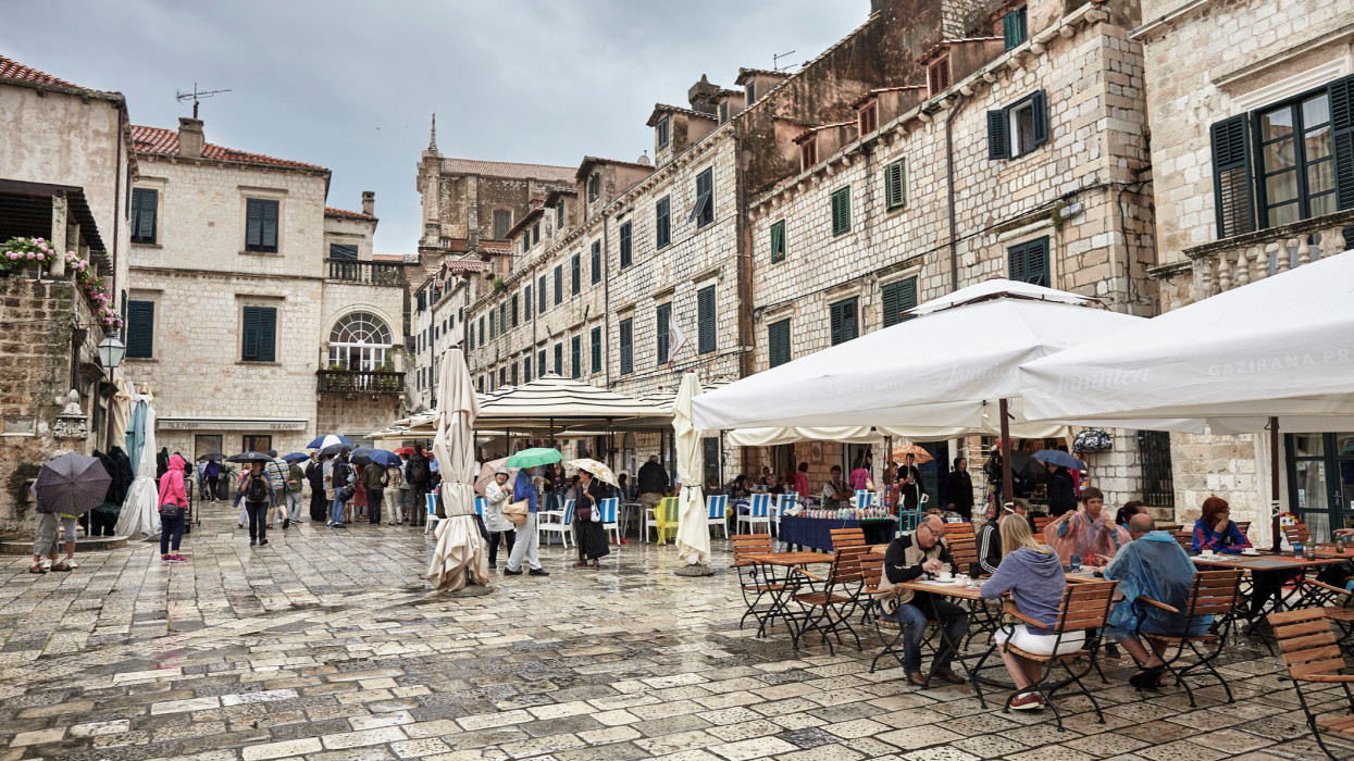 Dubrovnik, Croatia - June 15, 2014: turists sitting in restaurants and walking on city squere during rainy day