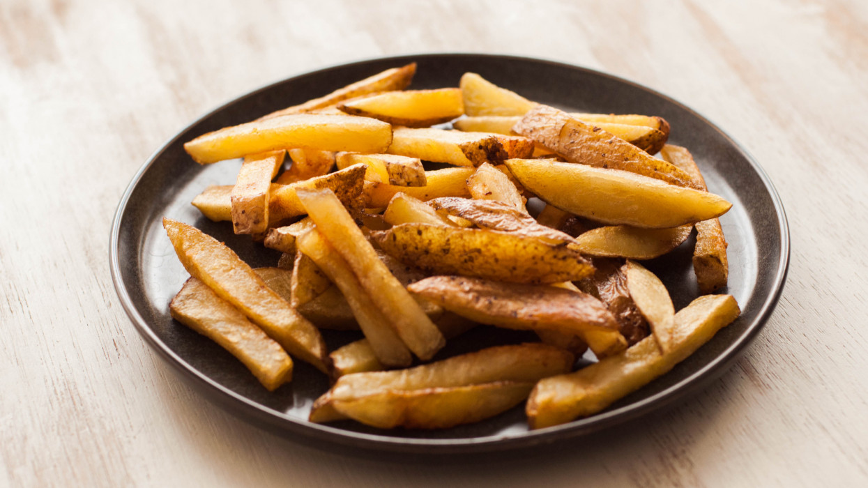 Still life of freshly cooked homemade french fries on a rustic plate and table