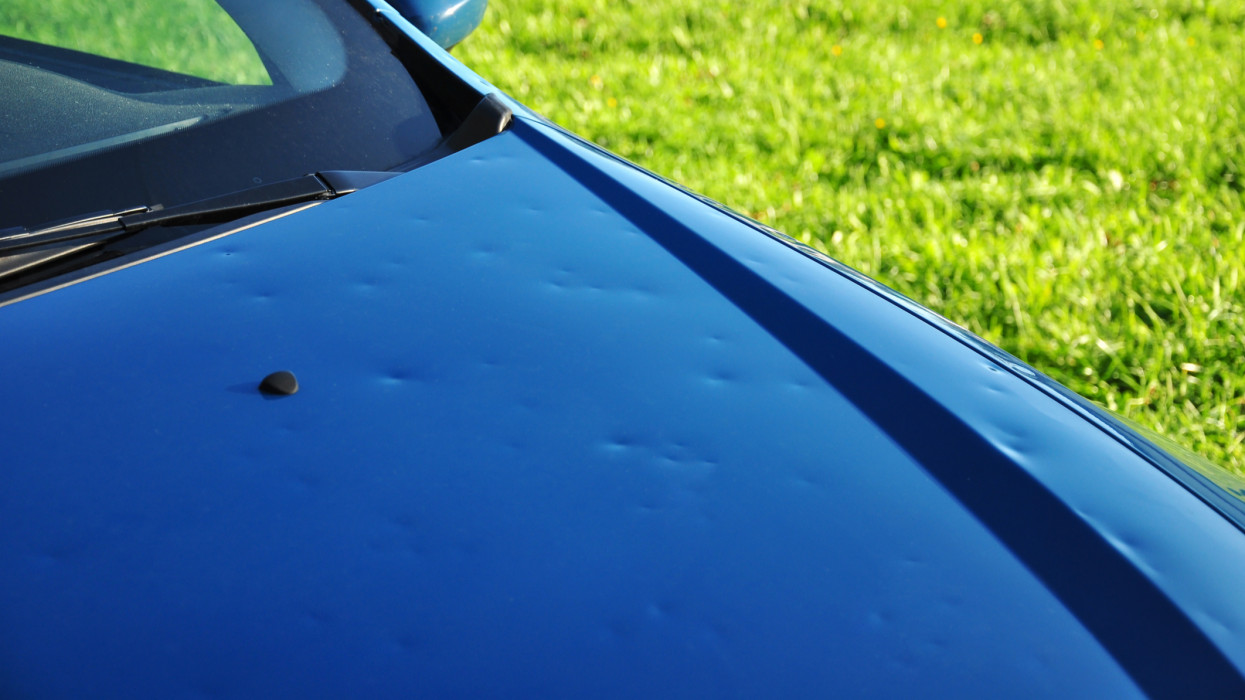 hail damage on the hood of a blue car