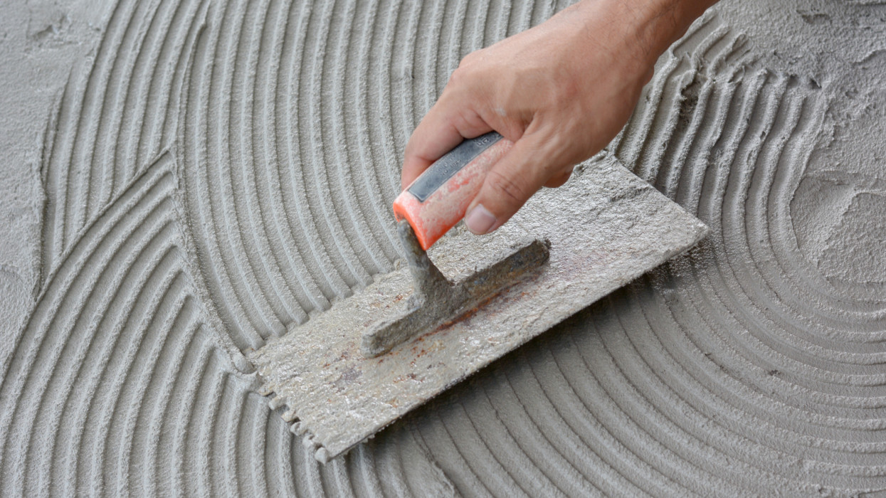 Hand on be bound with cement , do cement work, apply cement (over a surface)