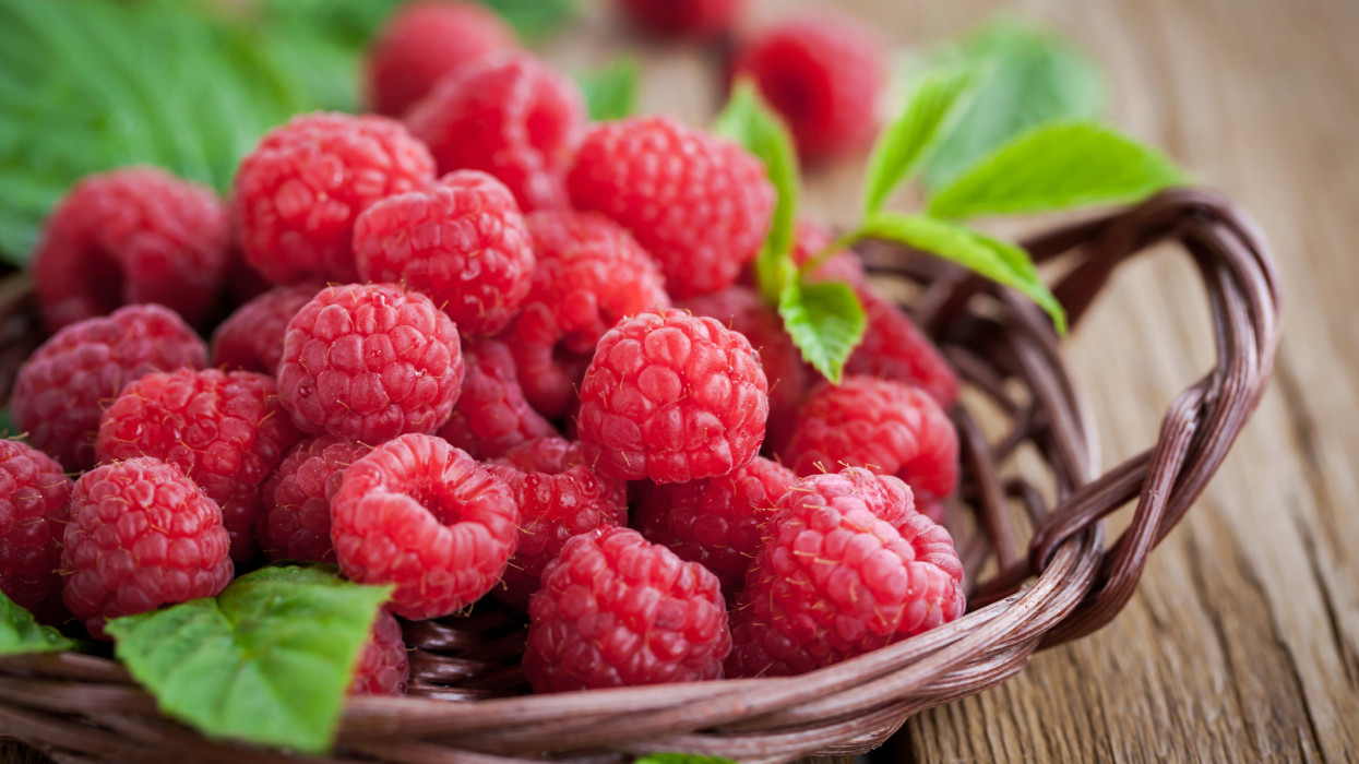 Fresh organic ripe raspberry with leaf in basket,  selective focus