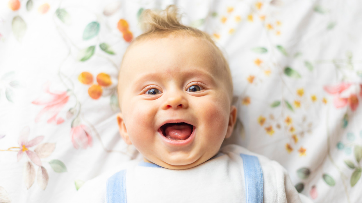 Photograph of a baby laughing in the bed