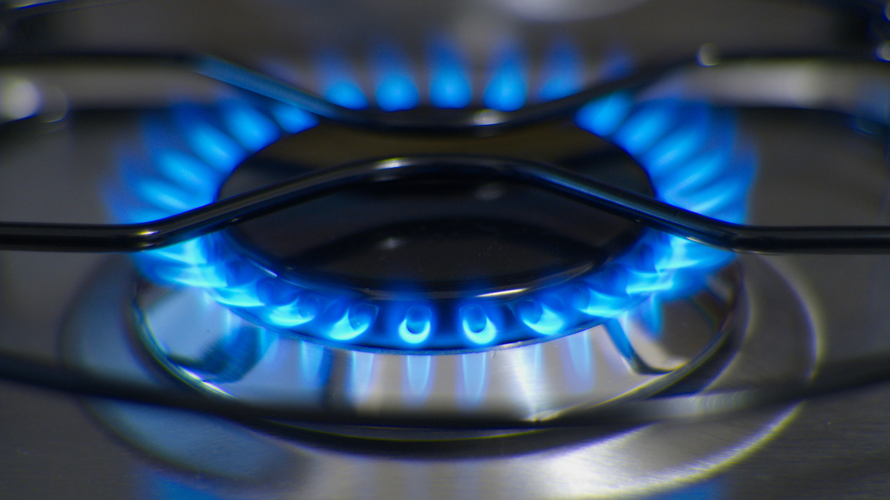 Close-up of flames of gas burner and iron trivet of stainless steel stove