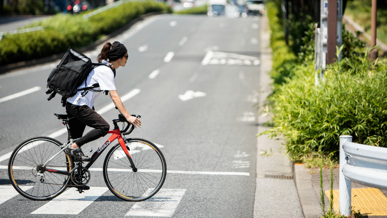 Uber Eats in Tokyo. Midsummer afternoon. He crosses the crosswalk. Avenue.