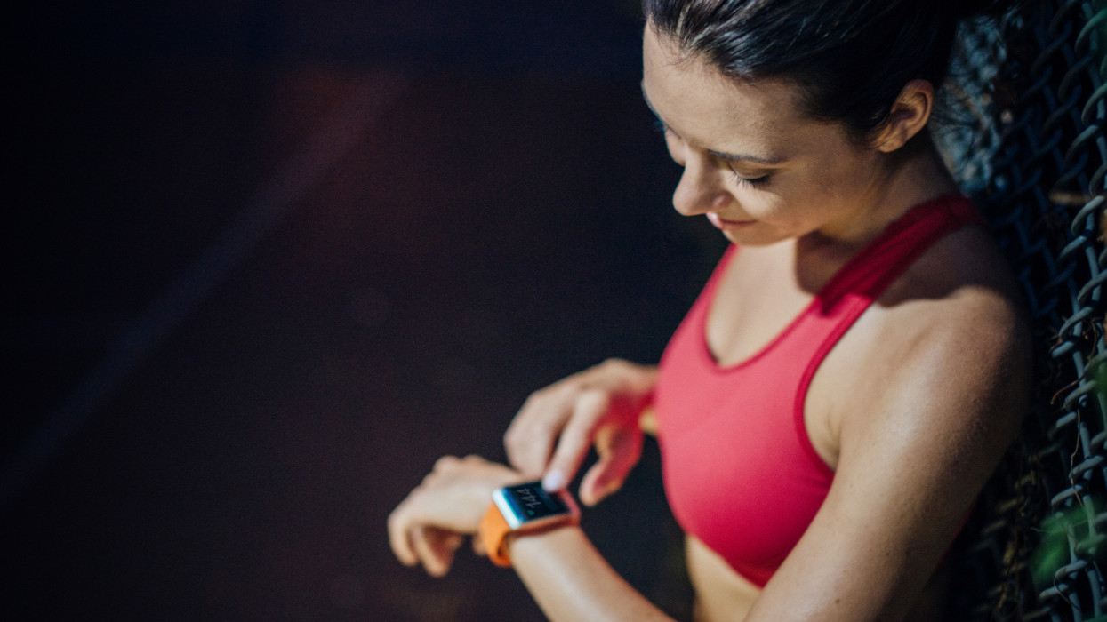 Woman checking pulse with smartwatch after doing some sport in the evening.