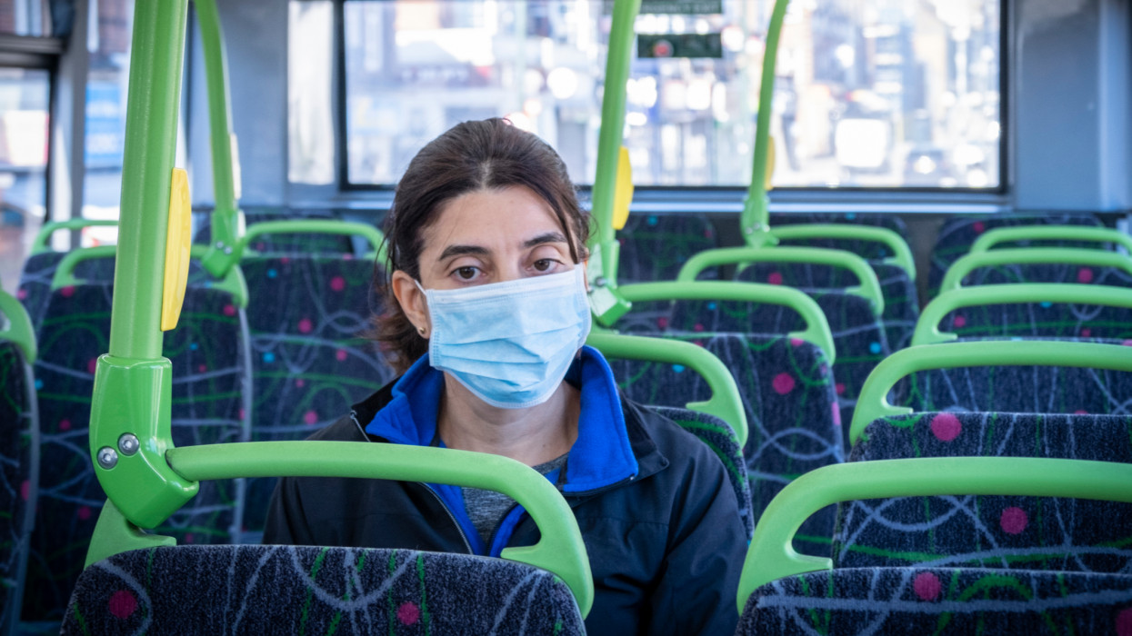 A commuter on her way to work using a face mask on a double-decker bus, during a health lockdown
