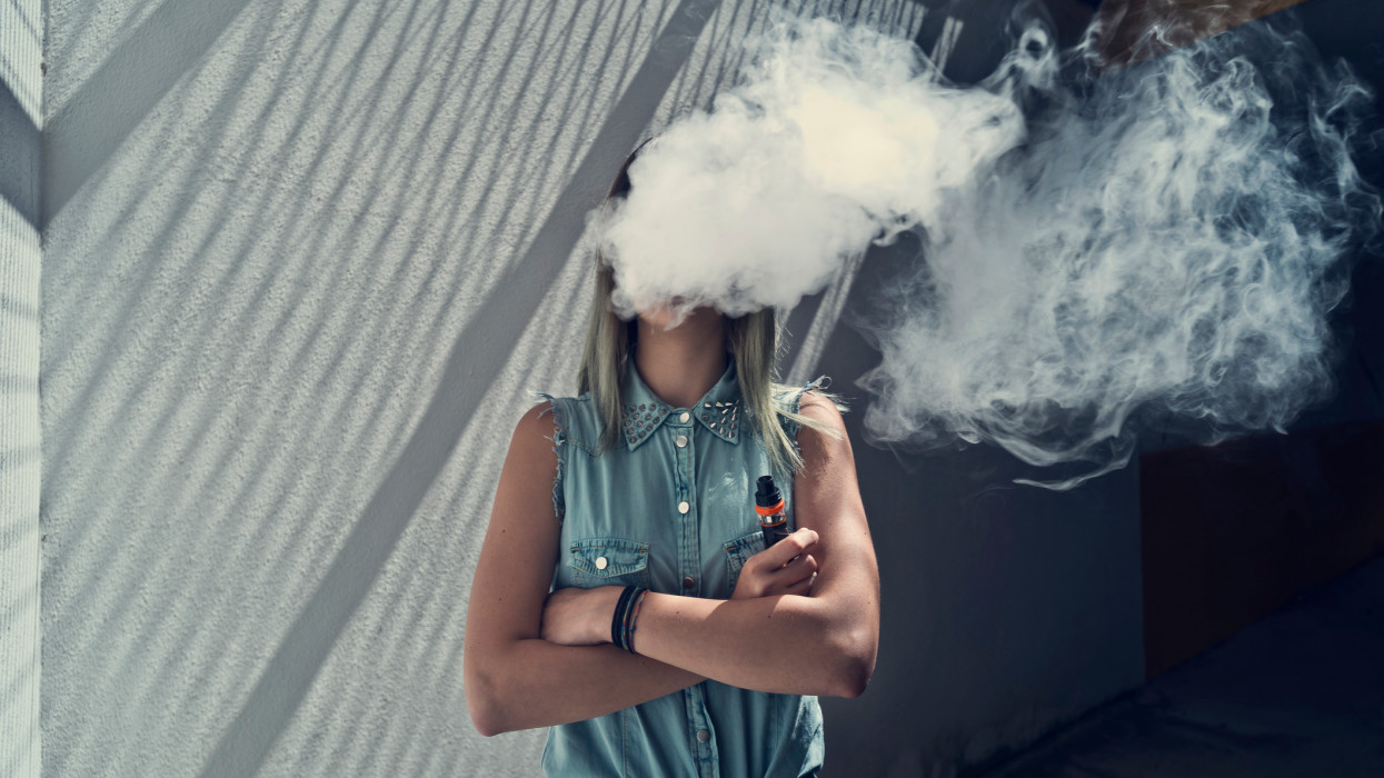 Young woman with her head in a cloud of vapor smoke cimlapi