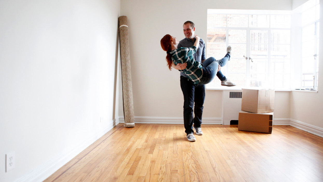 Man lifting woman in empty apartment