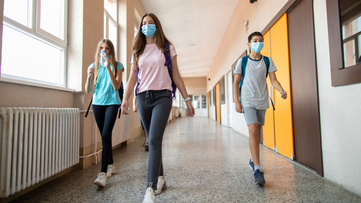 Elementary school students walking down the hallway in between classes. They wearing protective face masks during the corona virus outbreak to protect themselves