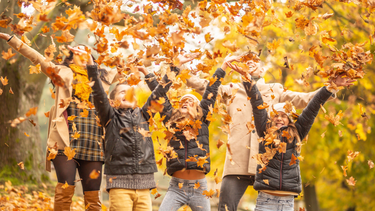 Family fun outdoors in the autumn by throwing fallen leaves up in the air.