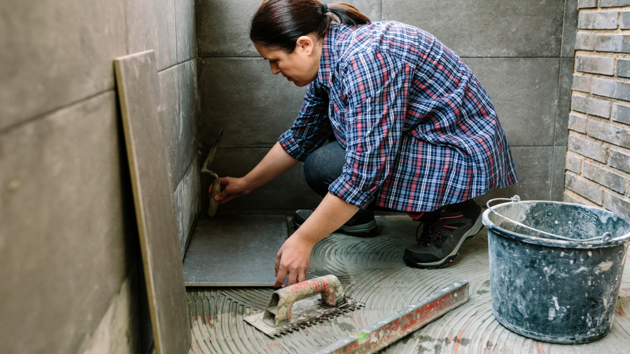 Female manual worker laying a new tile floor on a terrace