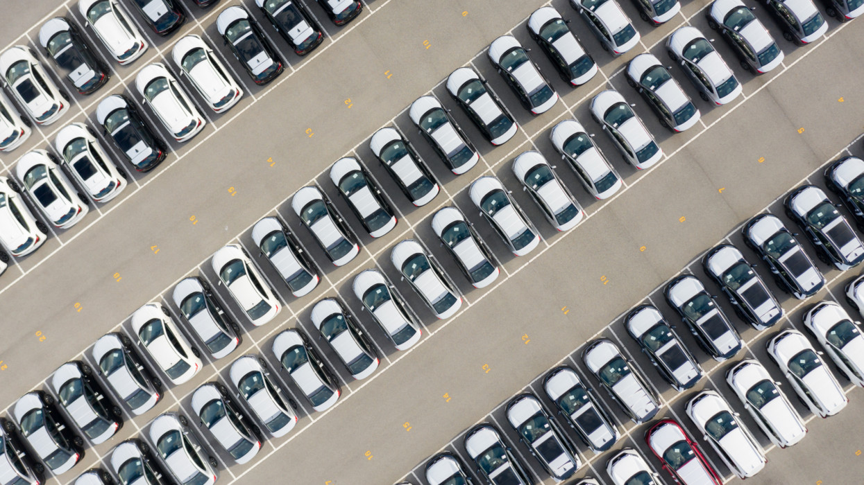 Aerial view new car lined up in the port for import and export business logistic to dealership for sale, Automobile and automotive car parking lot for commercial business industry.n