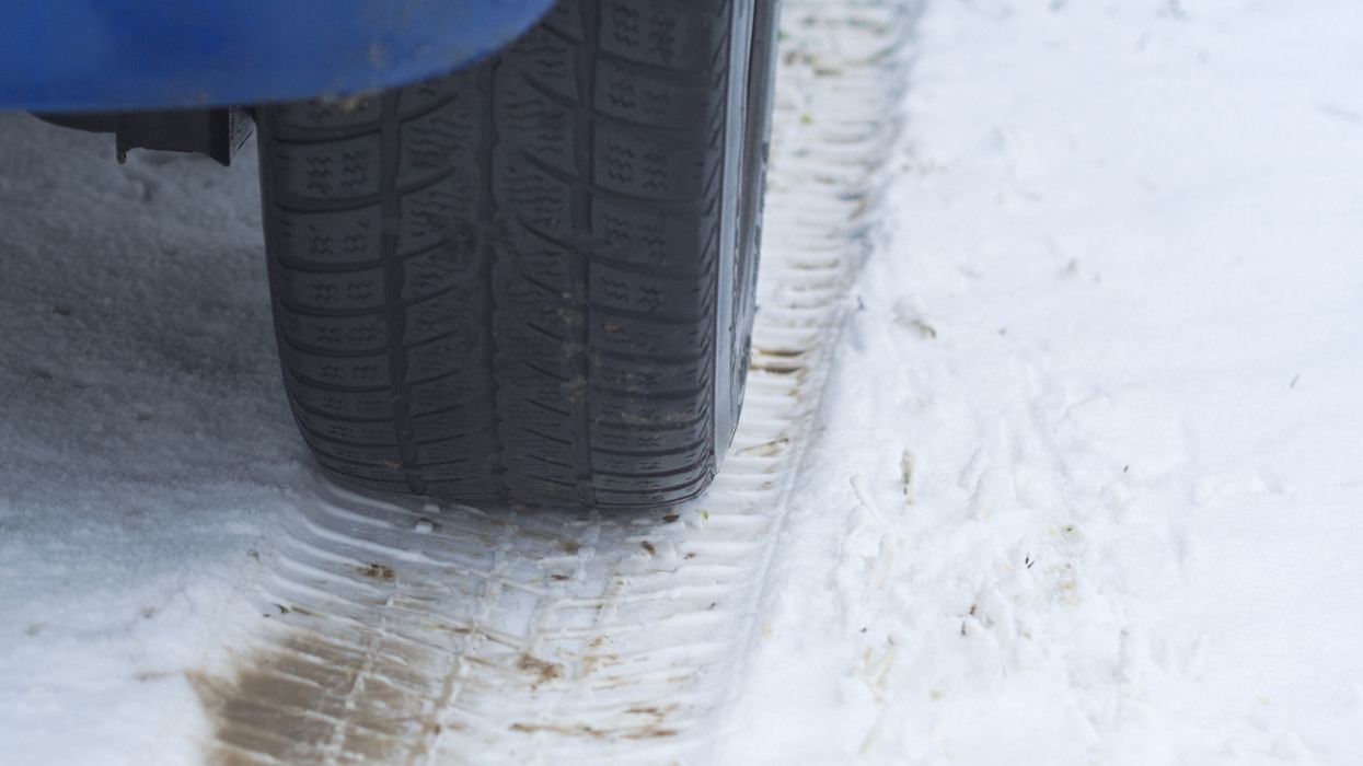 Car Tire on a Snowy Winter Road Closeup