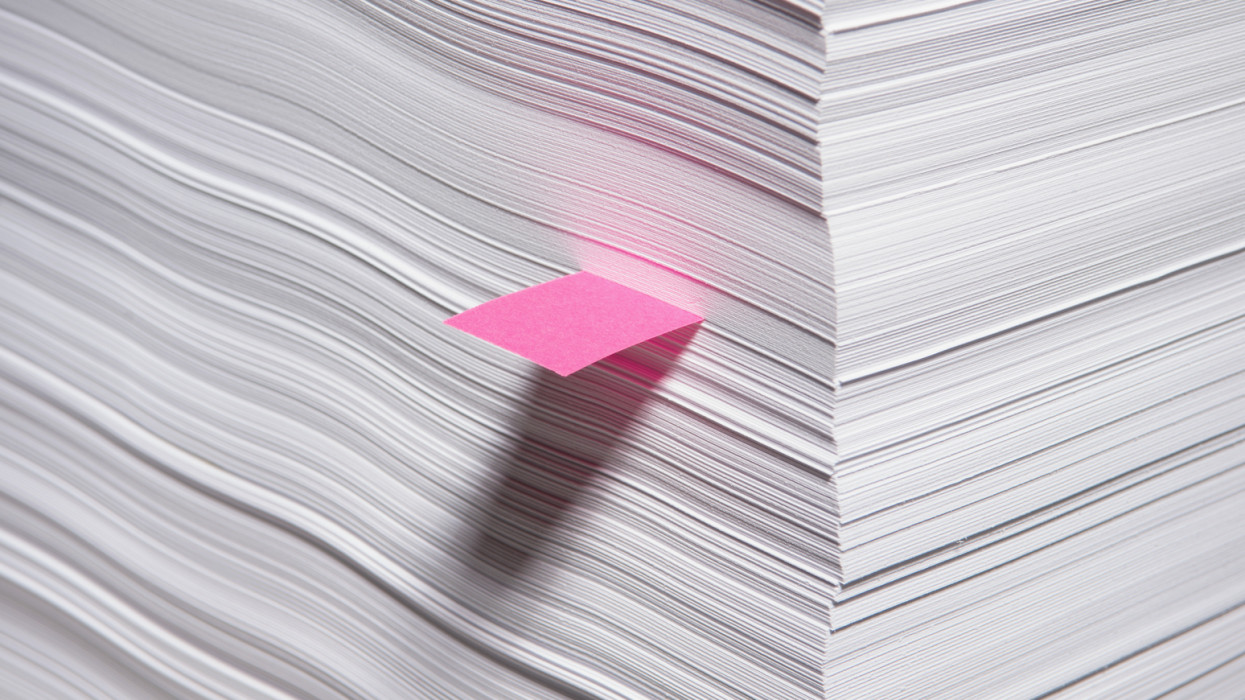 One sheet of paper in a stack, marked with a colored adhesive note