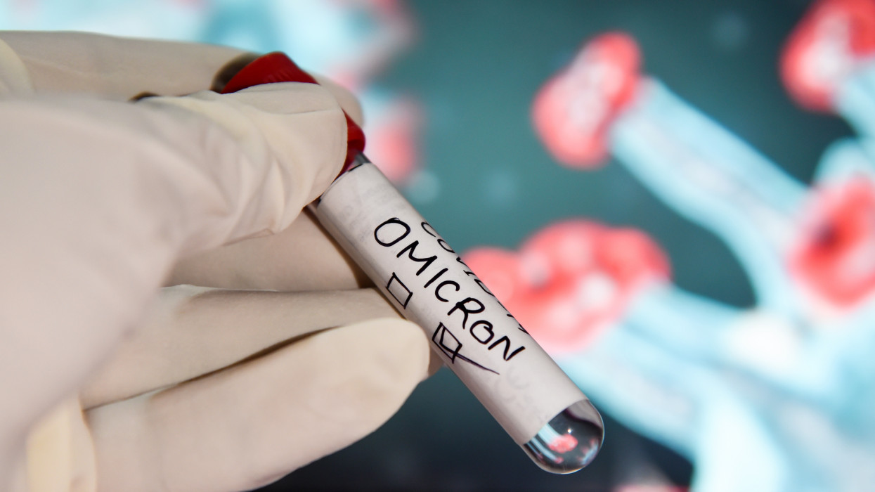 In this photo illustration, a health worker wearing gloves holding a test sample tubes labeled COVID-19 Omicron variant in front of a display. More than 150 confirmed cases of the Omicron variant have been detected in India.