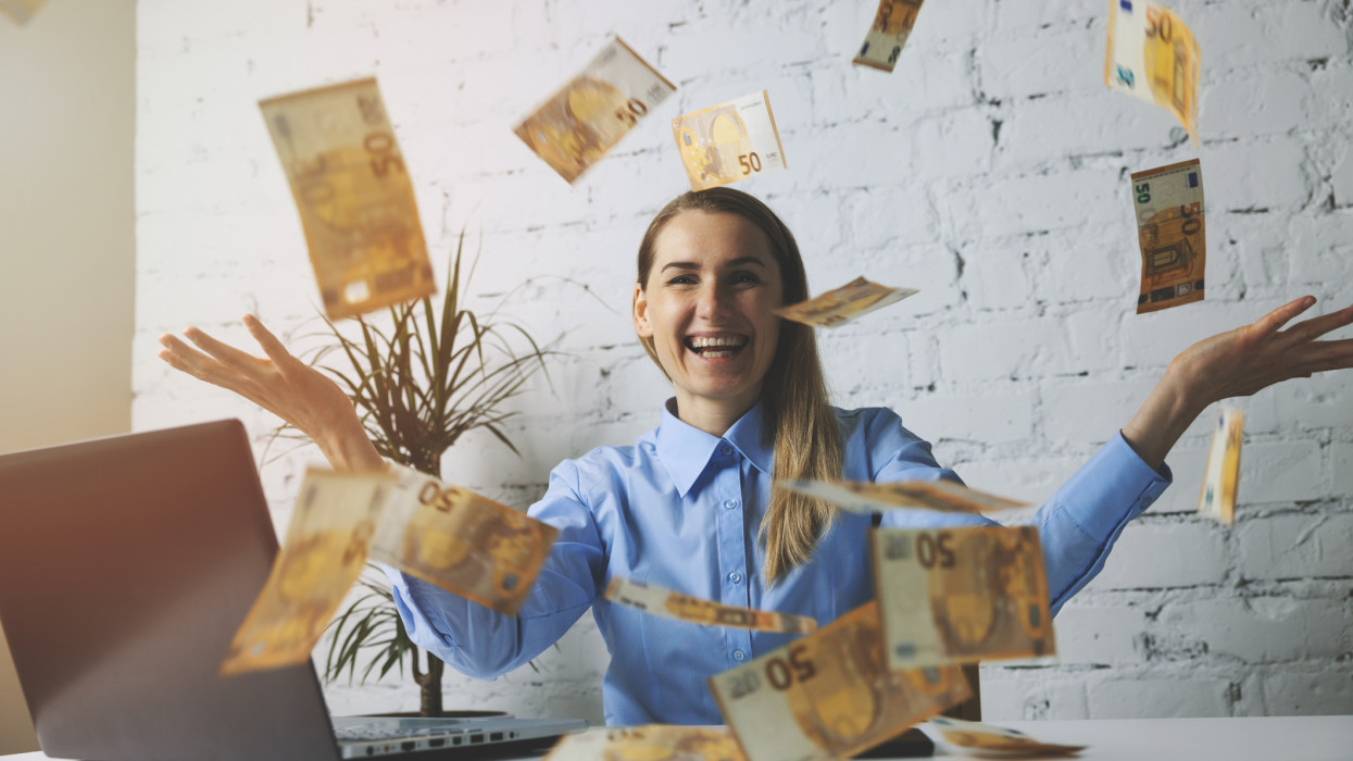 successful cheerful business woman throwing euro banknotes in office. falling money