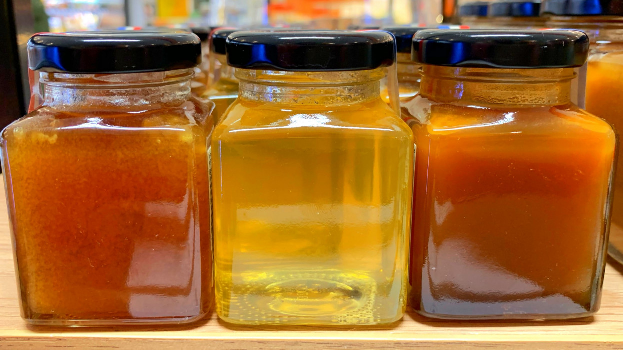 Three jars of clear honey, organic honey in farm shop, manuka honey and crystallised honey
