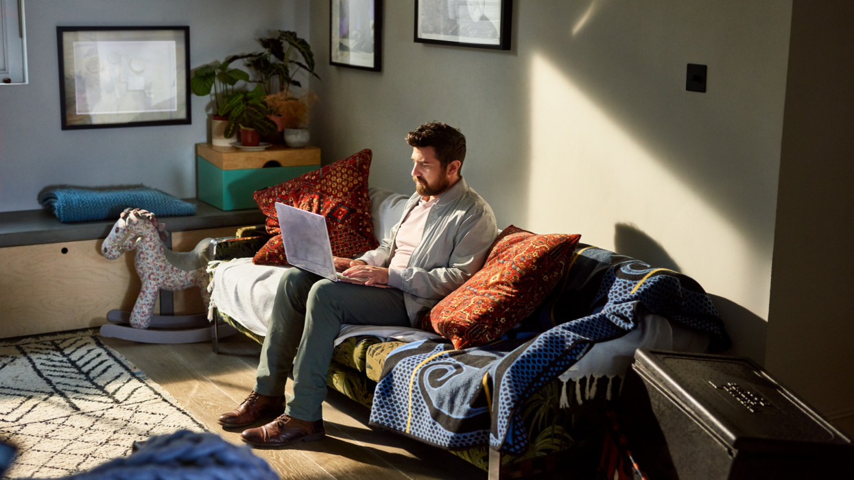 Portrait of man on sofa using laptop in living room, small business, online, industrious, efficiency