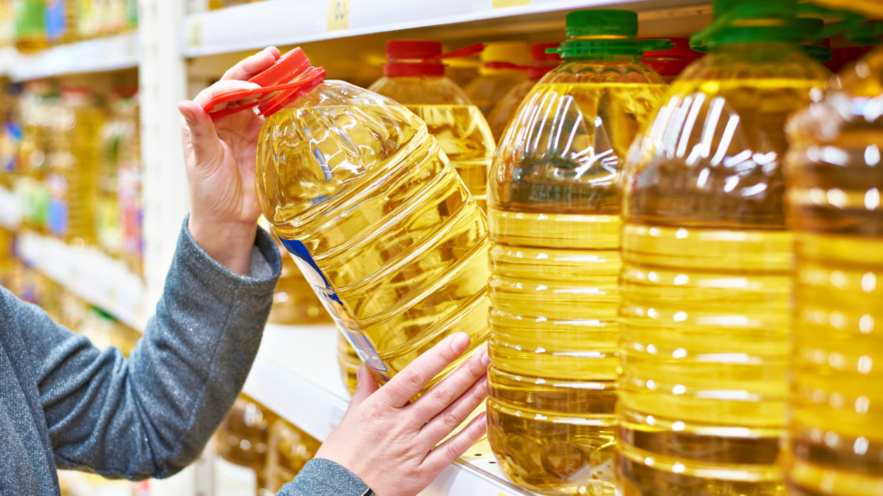 Big plastic bottle of olive oil in the hand of the buyer at the grocery store