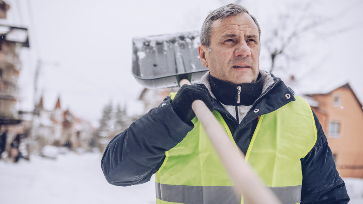 One man, prepared for clean the street full on snow, holding snow shovel.