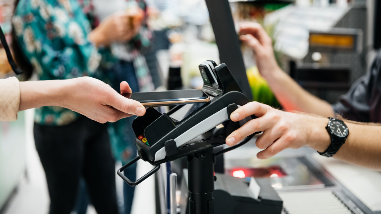 A close up of a contactless payment being made using a smartphone at the supermarket.