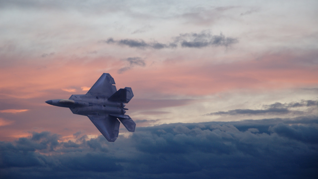 Dark and moody. An F22 fighter jet cuts across the sky at dusk.