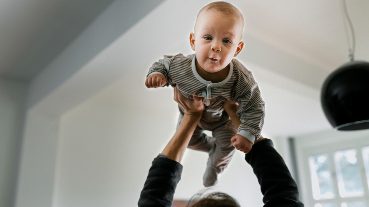 Close-up of father bonding with son. Father is lifting baby son into the air. Focus on baby.