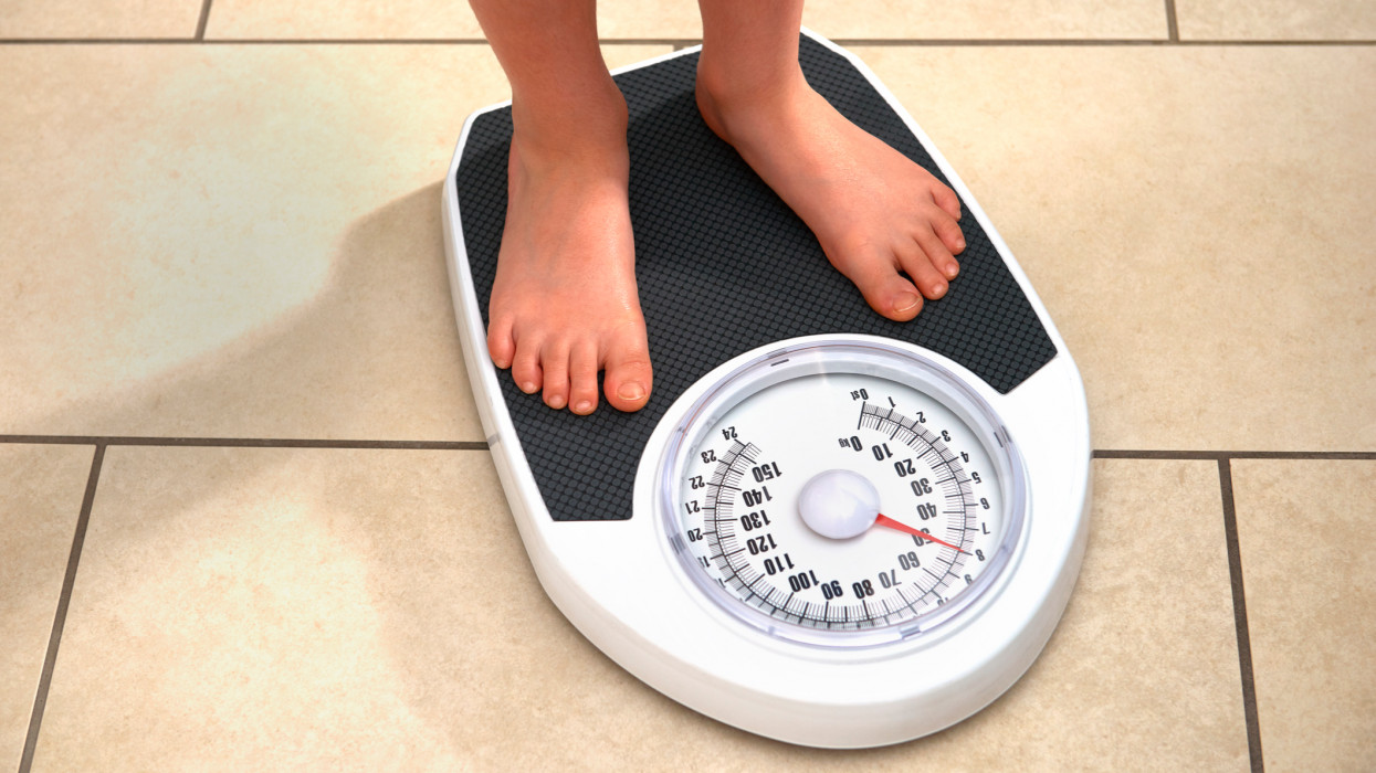 8 year old boy weighing himself on bathroom scales at home