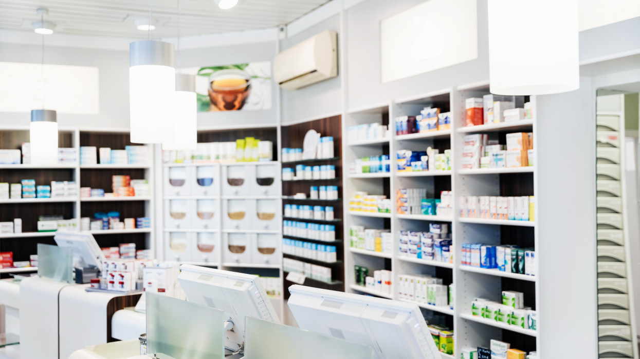 A pharmacy counter before the store has opened, with medicine on display behind the checkouts.