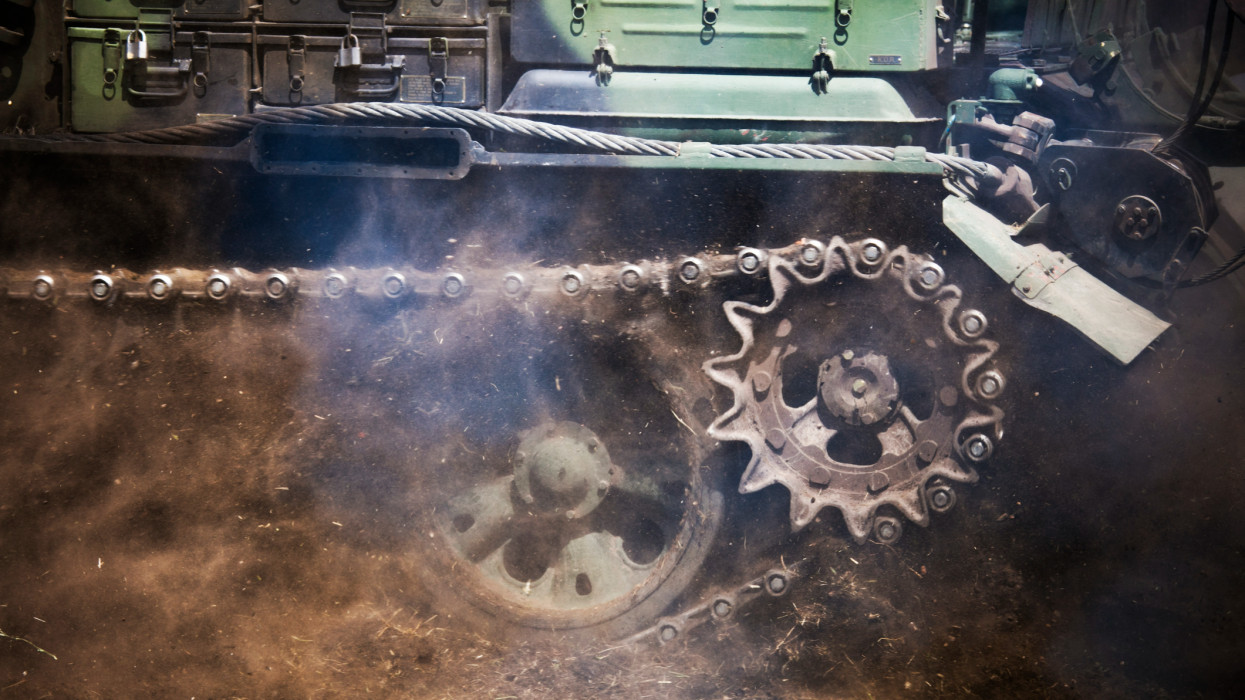 Close-Up of Tank Tracks in movement pulling dirt in the air.