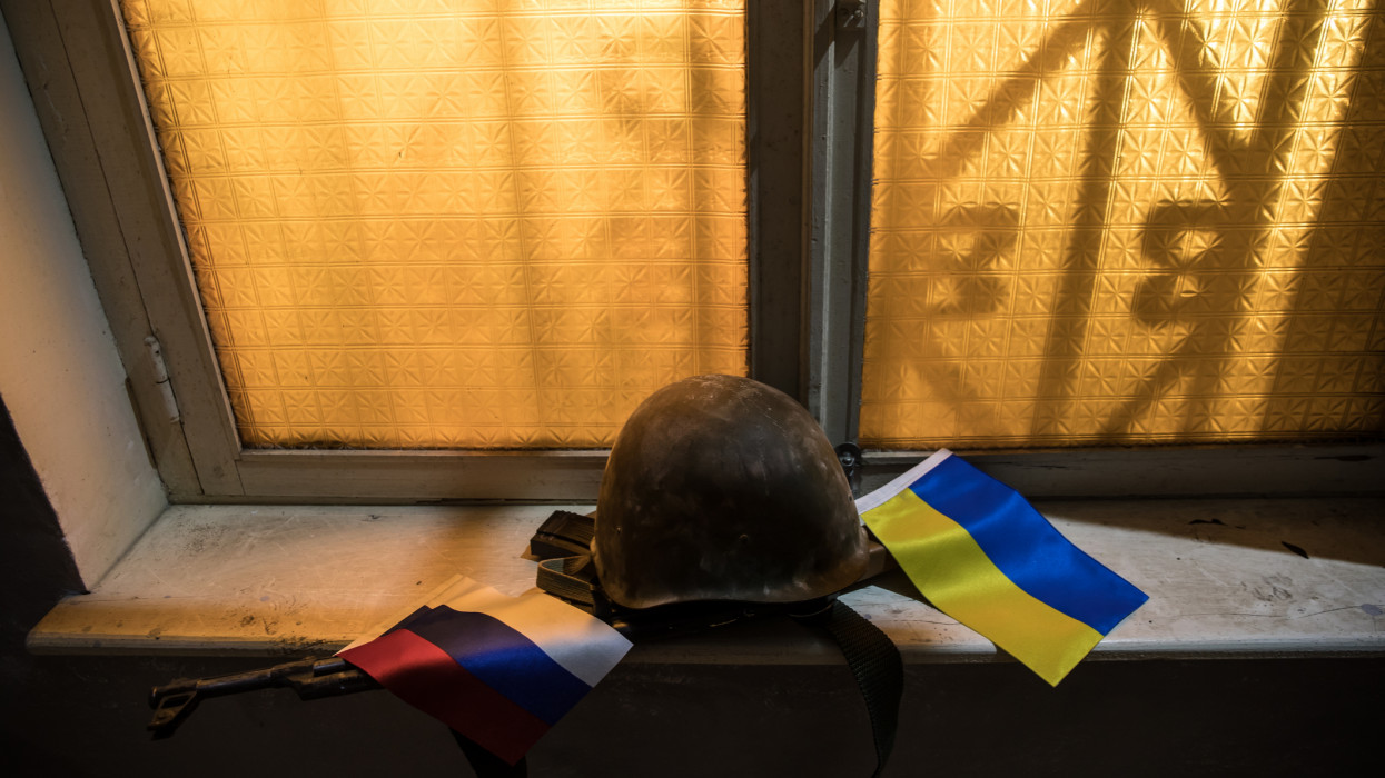 Conceptual photo of war between Russia and Ukraine. Ukraine and Russia flags on windowsill at night. Old creepy room with window. Explosion outside.