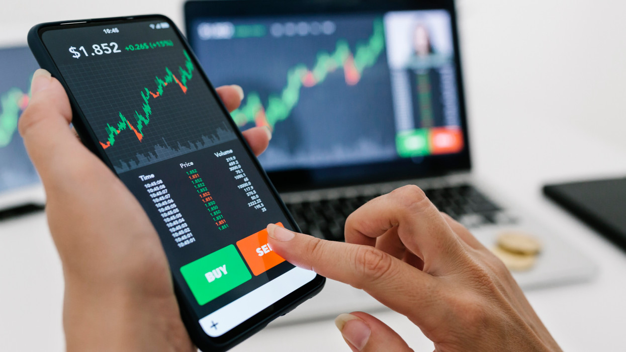 Female manager selling cryptocurrencies through mobile phone app. Stock market, investment and cryptocurrencies concept